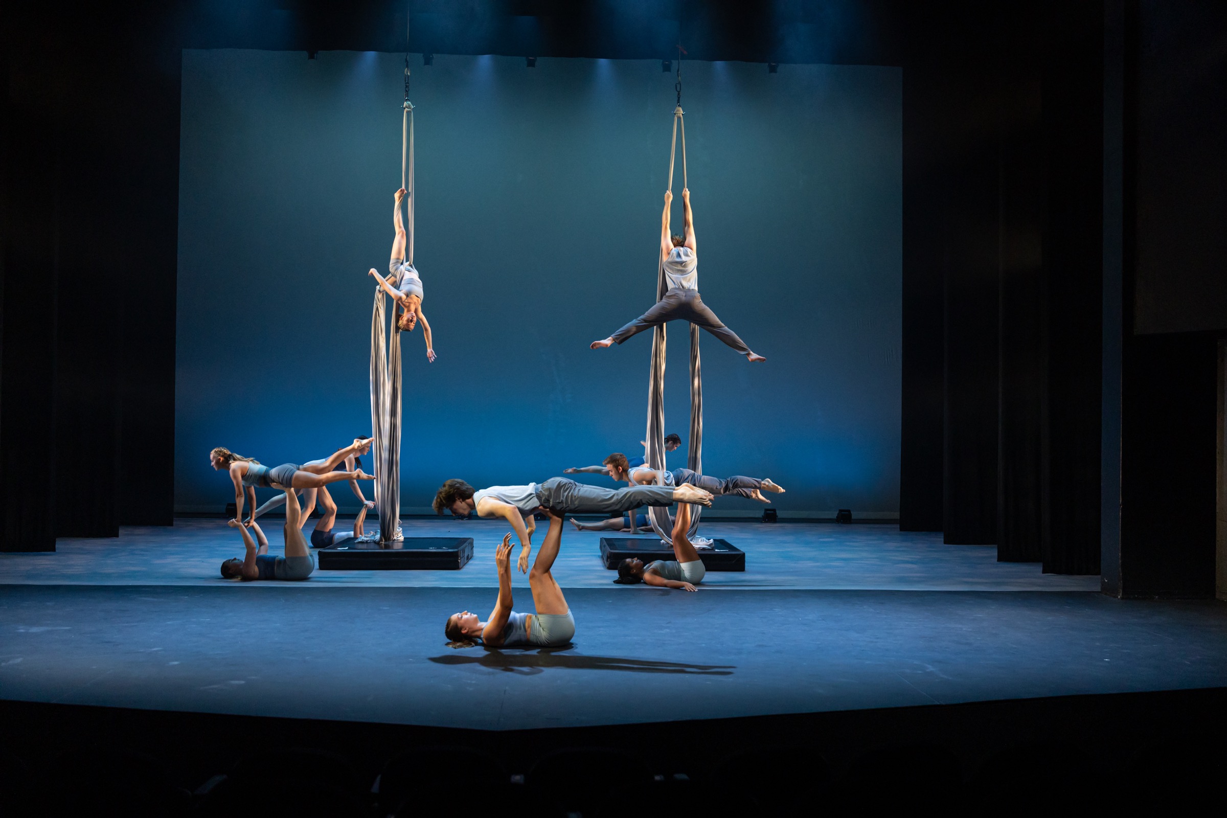Flying/Falling ensemble with aerial fabric performers and partnered floorwork under blue lighting