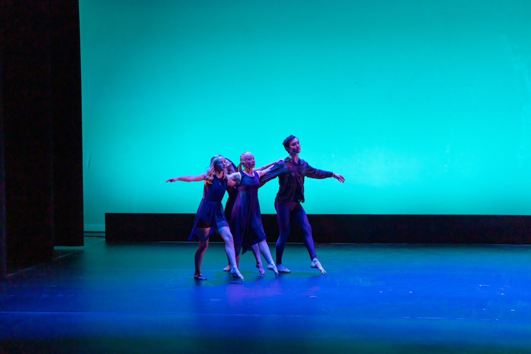 A Lamp to My Feet ensemble performing in a clustered formation under teal lighting