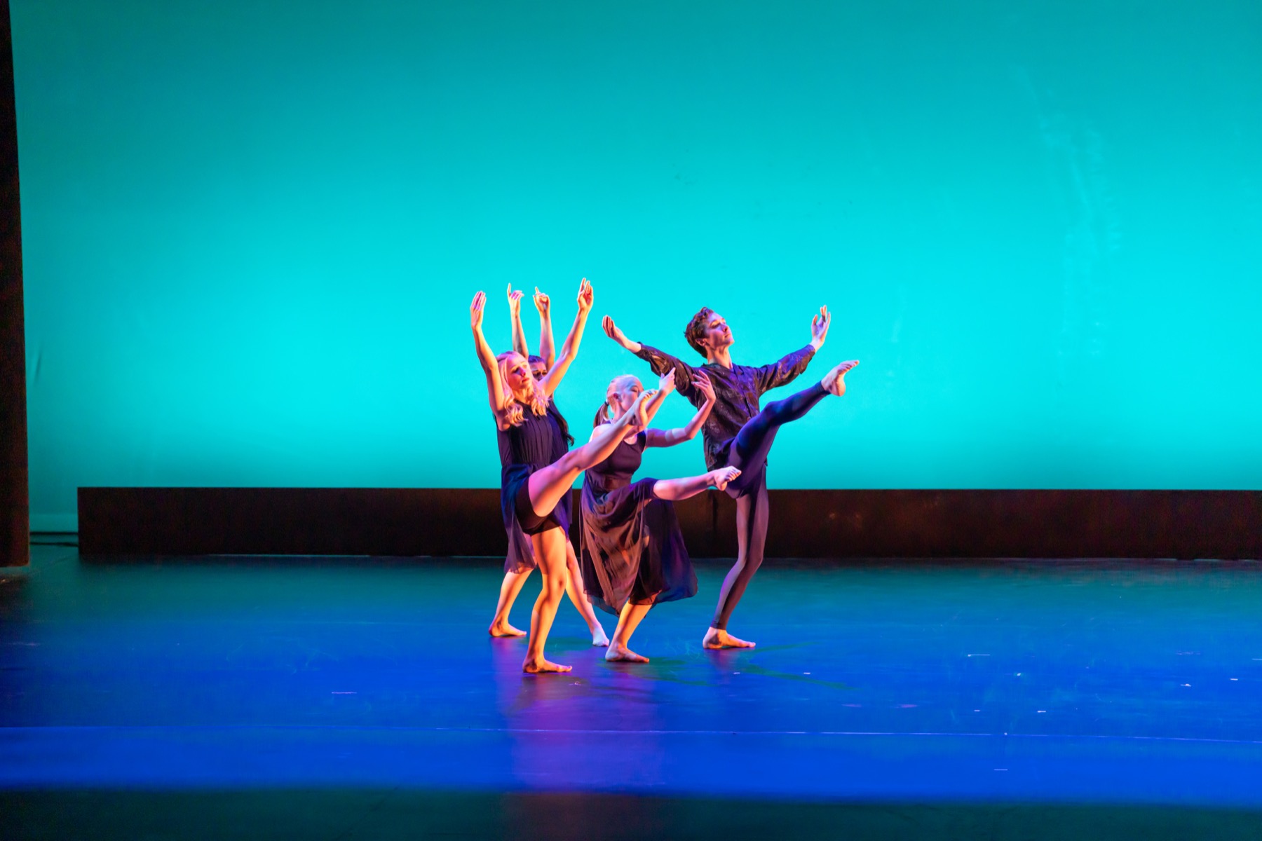 A Lamp to My Feet dancers reaching upward in a teal-lit stage phrase