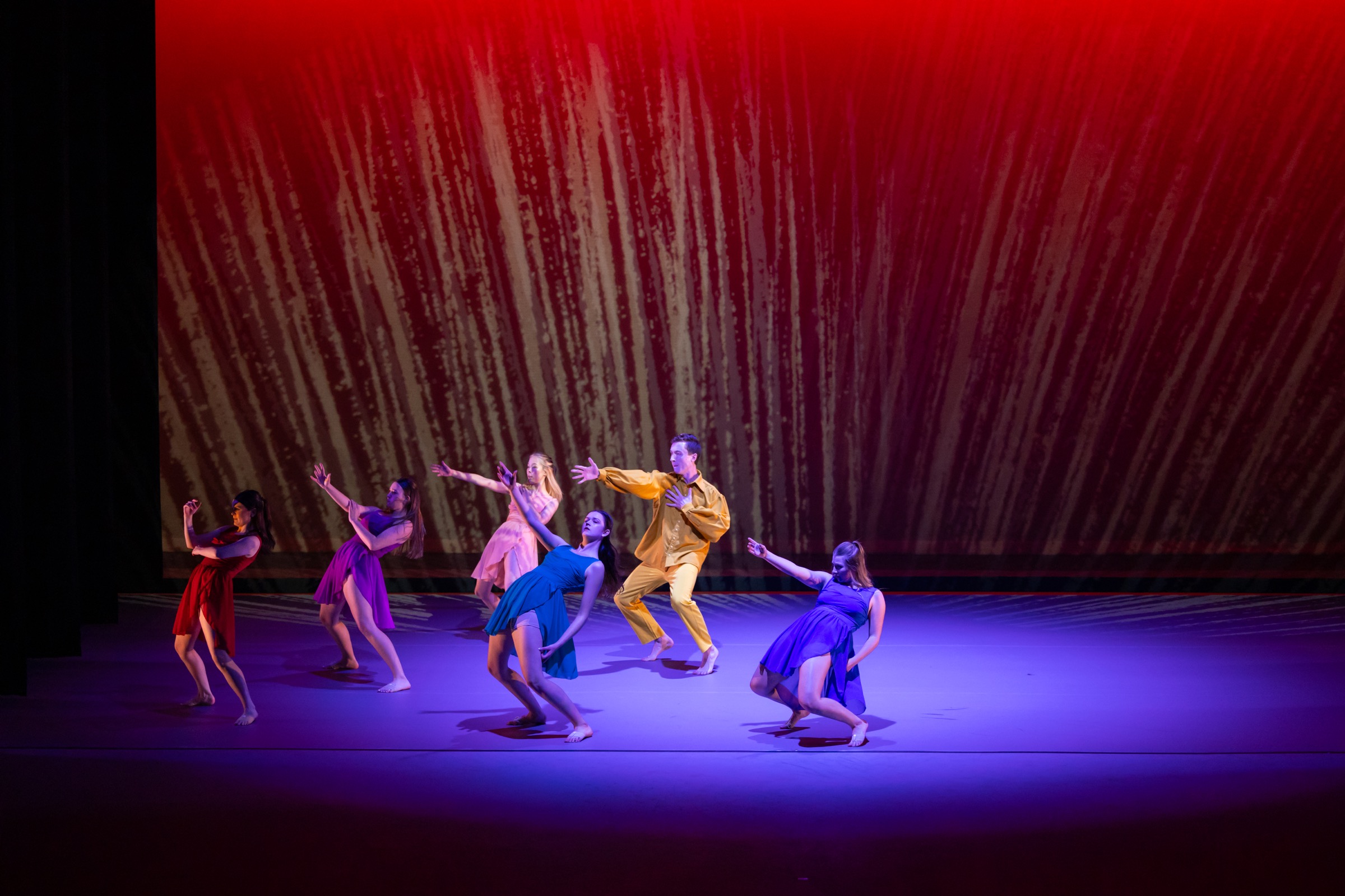 Strife ensemble reaching outward under red and purple stage lighting