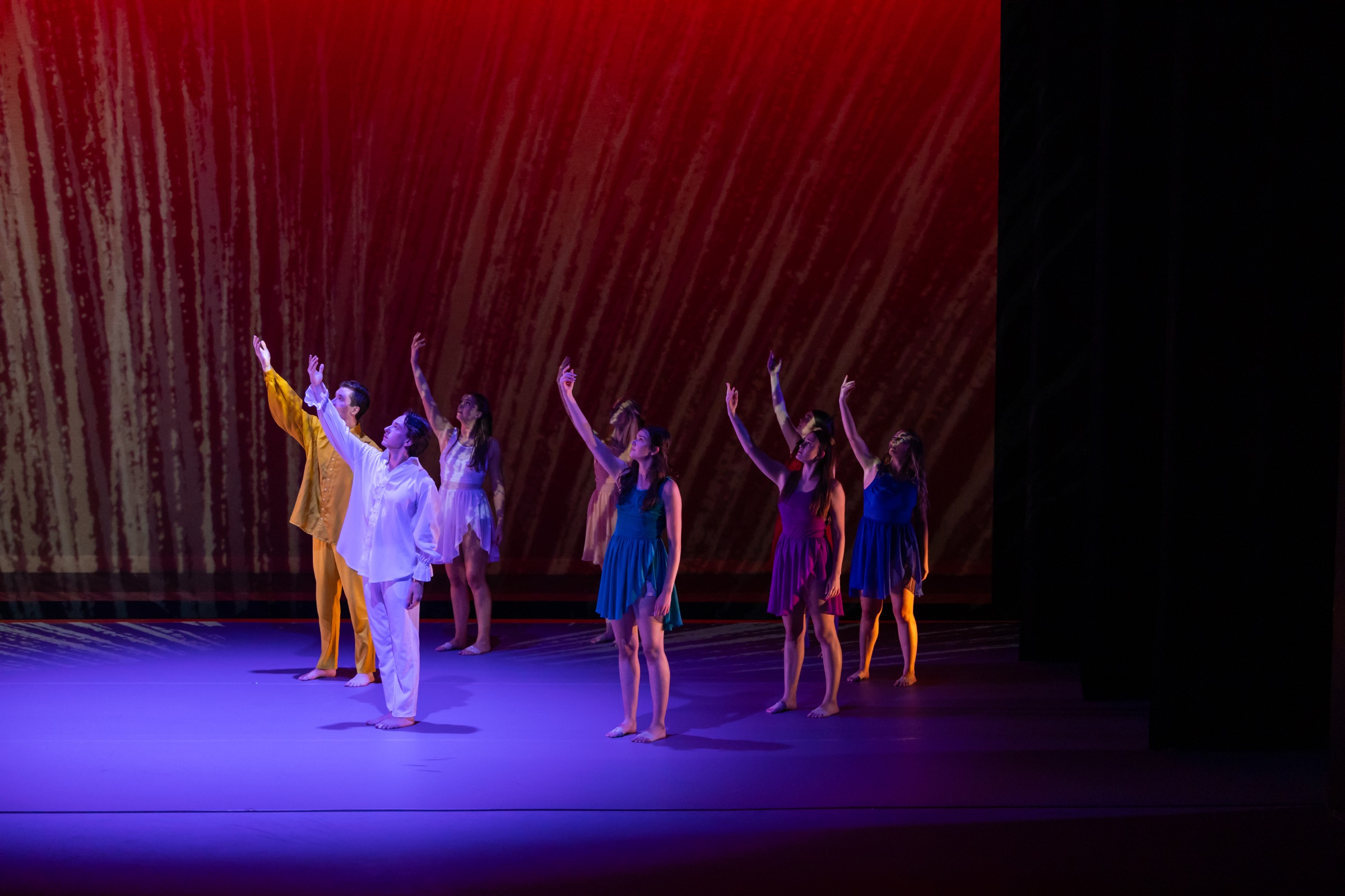 Strife ensemble standing in a diagonal formation under red lighting